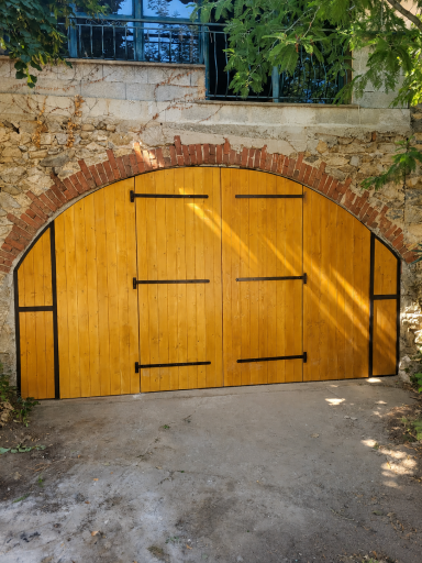 Porte de garage en épicéa à double battant sous un arc en pierre